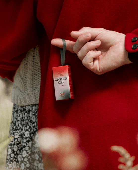 An ornamental holiday package dangles from a man’s finger hidden behind his back.