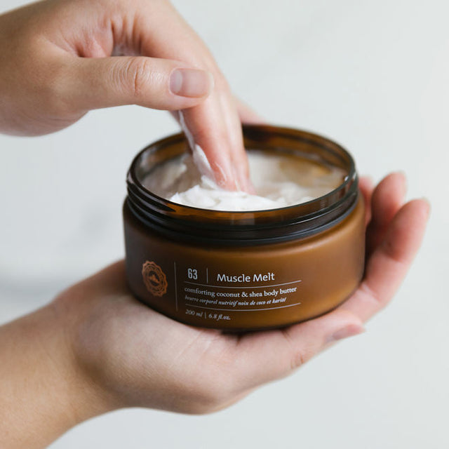 A pair of hands scooping out some muscle melt body butter 