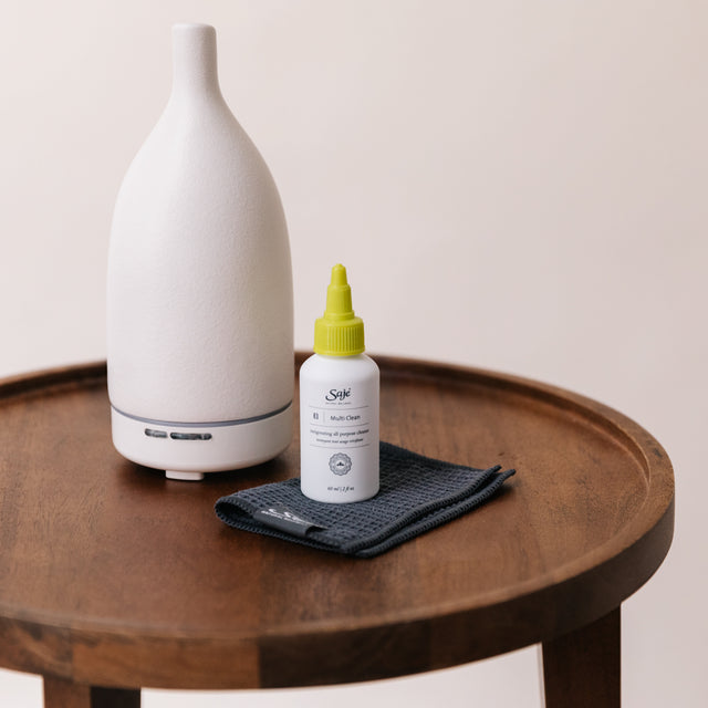 Diffuser cleaning kit next to an Aroma Om white diffuser on a round wooden side table