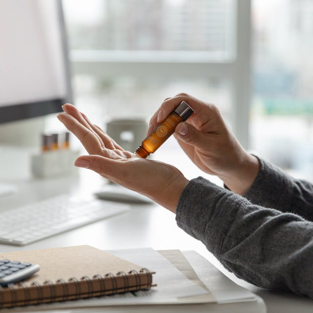 A person applying Unwind calming oil blend roll-on onto their pulse points in their hand